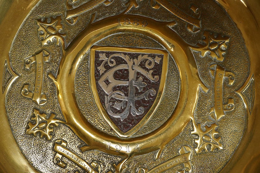 An embossed brass arts and crafts alms charger with inscriptions, 51cm in diameter